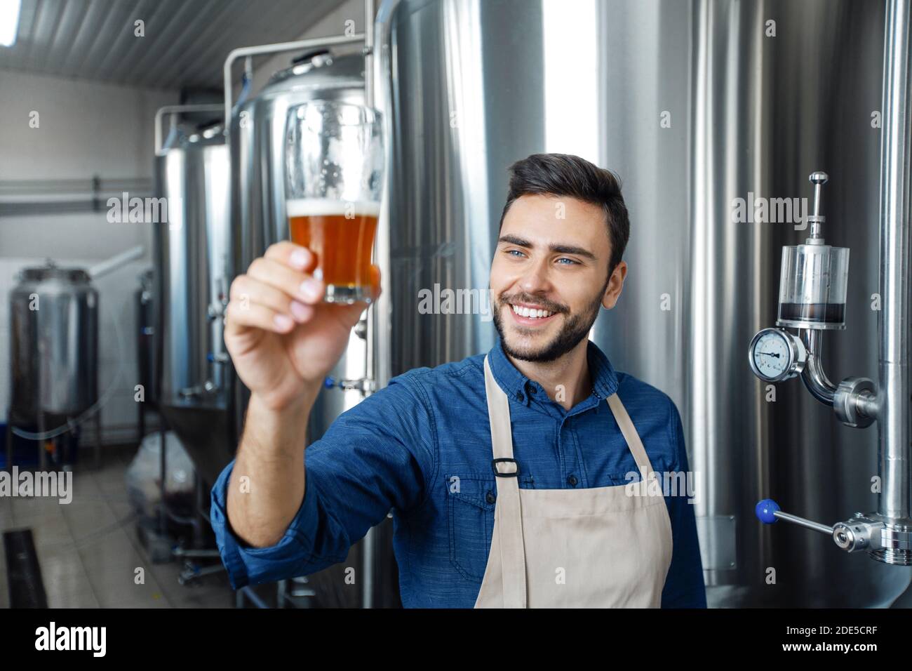 Birreria professionale che assaggia la birra in vetro alla produzione Foto Stock