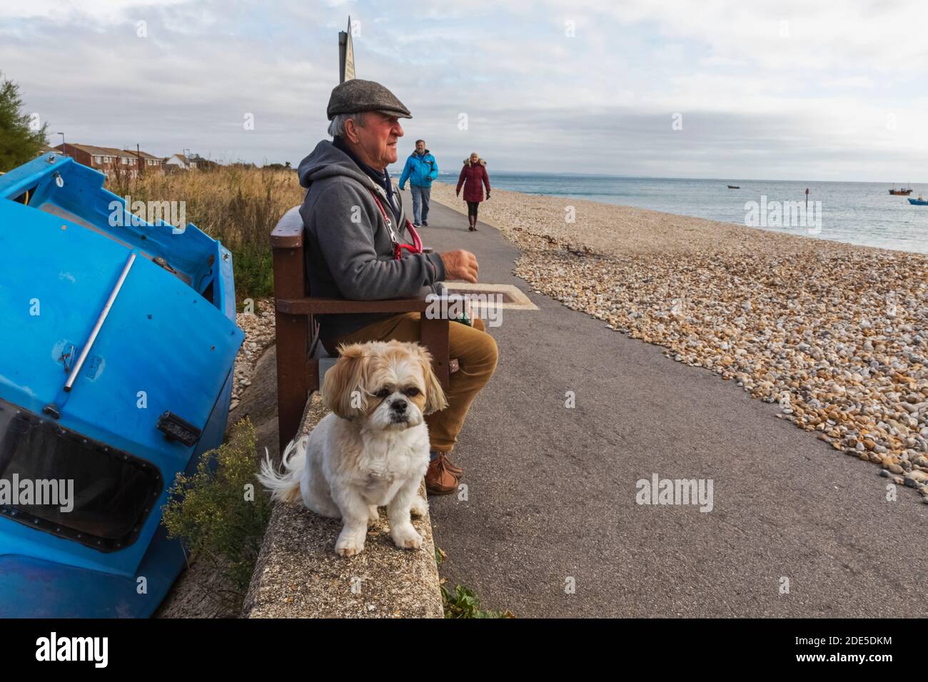 Inghilterra, Sussex occidentale, Chichester, Selsey Bill, uomo anziano seduto con cane sul fronte mare Foto Stock