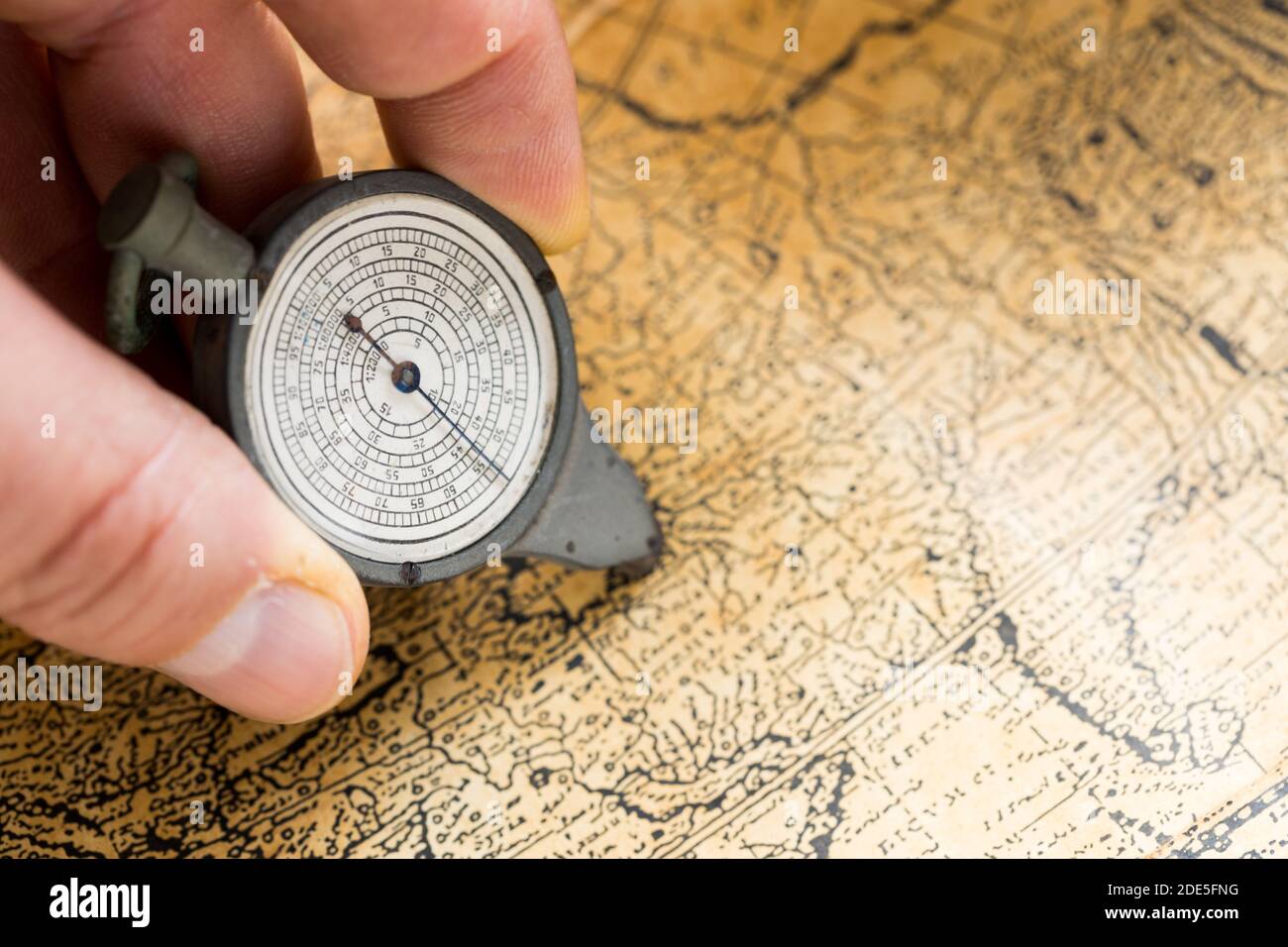 Tenuto nel corvestore a mano per misurare la distanza sulla mappa, stile vintage Foto Stock