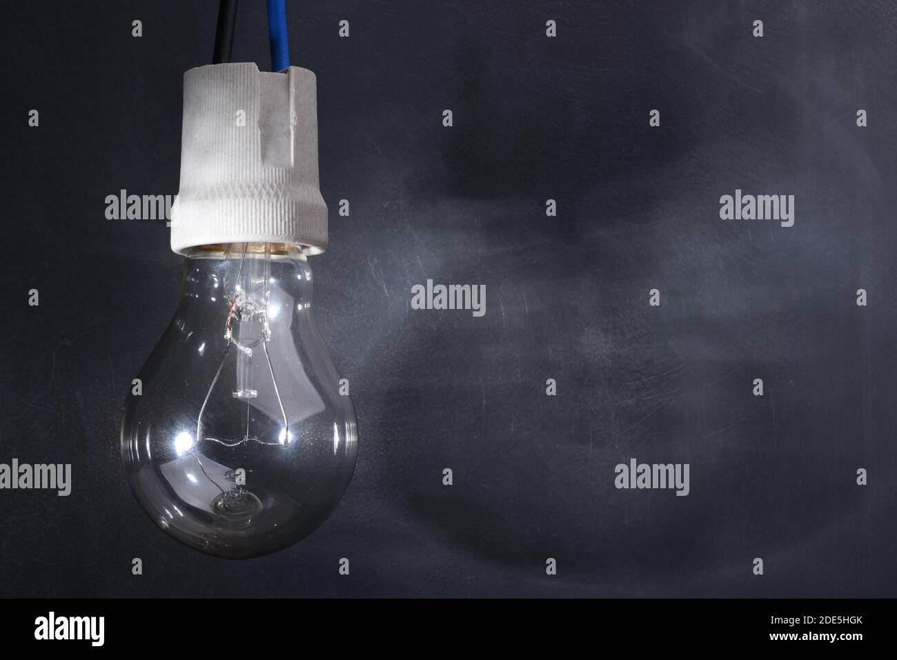 Lampadina sul cavo elettrico con ombra in ambienti bui Foto Stock