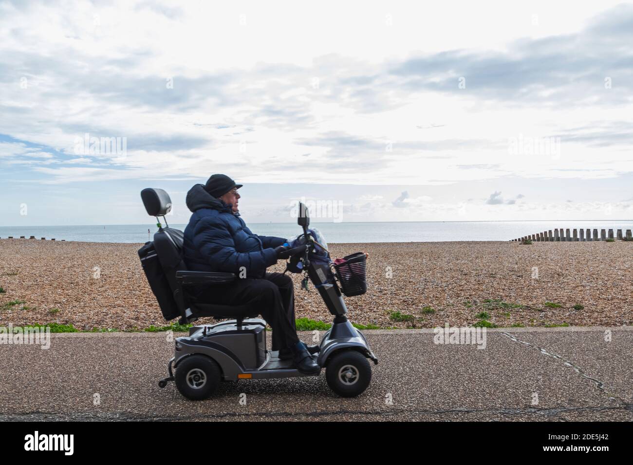 Inghilterra, East Sussex, Eastbourne, uomo anziano sulla passeggiata Eastbourne Seafront in scooter di mobilità Foto Stock