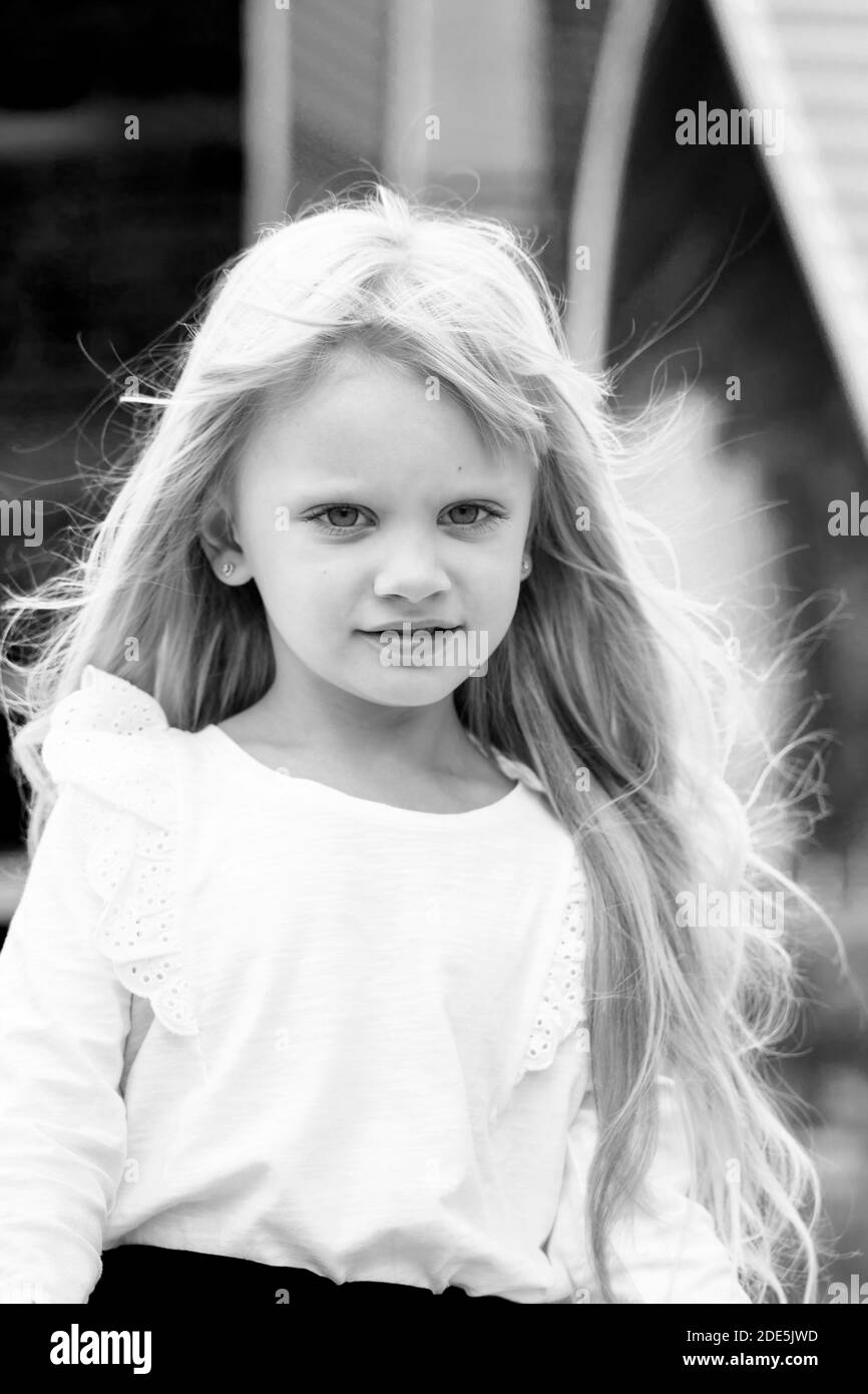 ritratto in bianco e nero di una bella bambina bionda in una blusa bianca sullo sfondo di grattacieli Foto Stock
