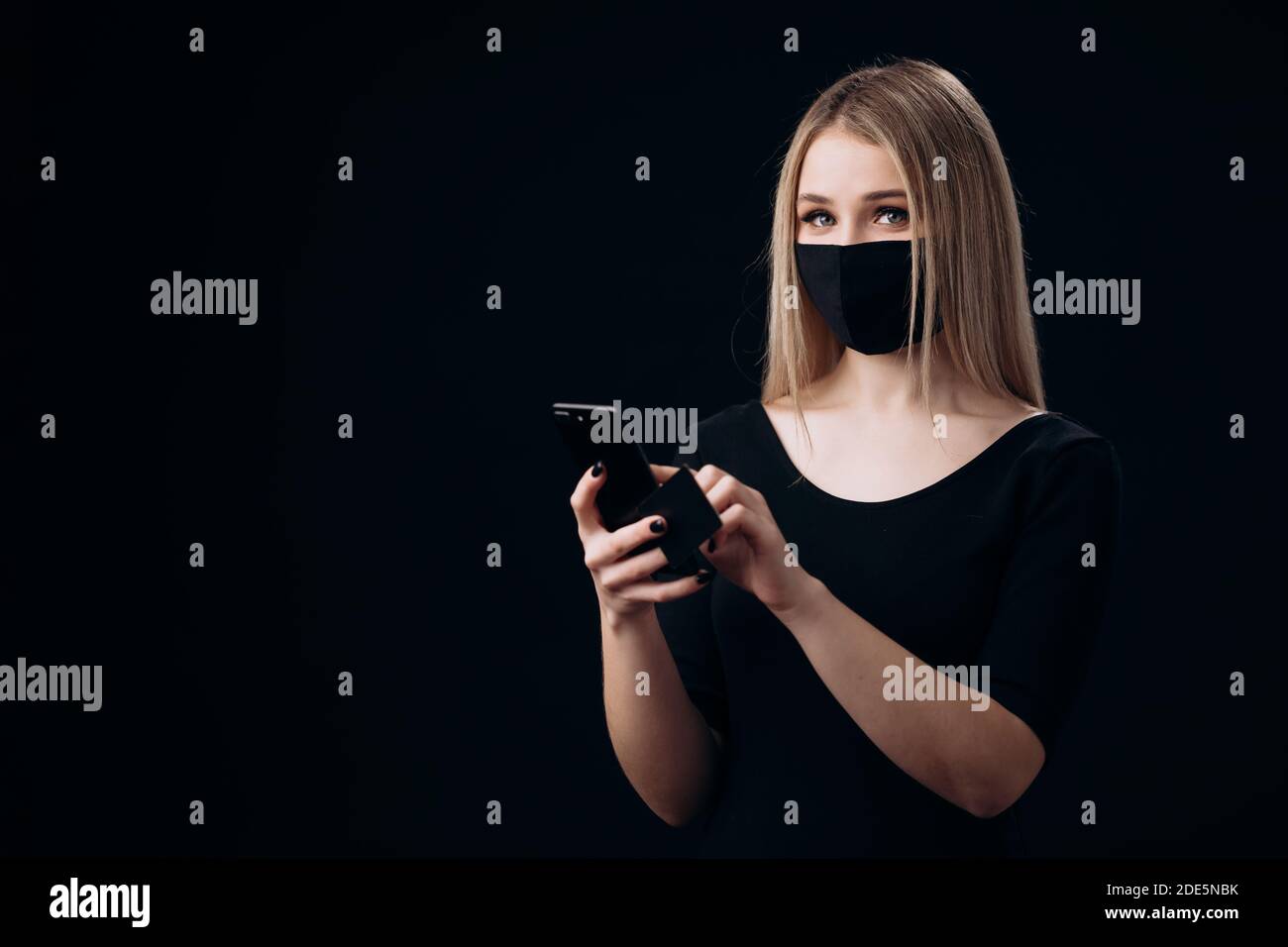 Biondo in maschera con carta di credito e cellulare per lo shopping Foto Stock