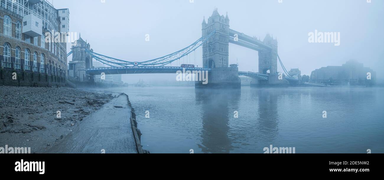 Tower Bridge e autobus di Londra con il Tamigi in atmosfera nebbiosa e blu, condizioni atmosferiche umide nel centro di Londra sul Coronavirus Covid-19 Lockdown giorno uno, Inghilterra, Regno Unito Foto Stock