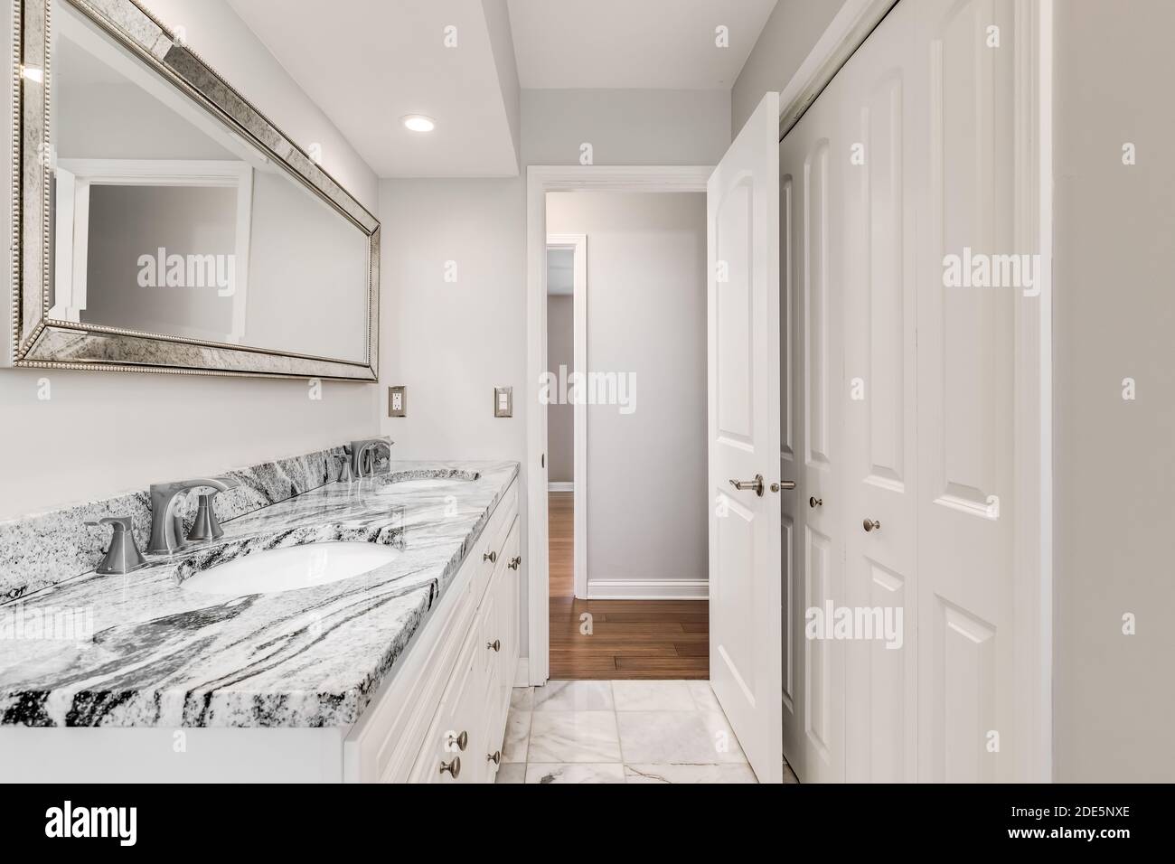 Bagno bianco con piano di granito nero e grigio e pavimenti piastrellati in marmo. Foto Stock