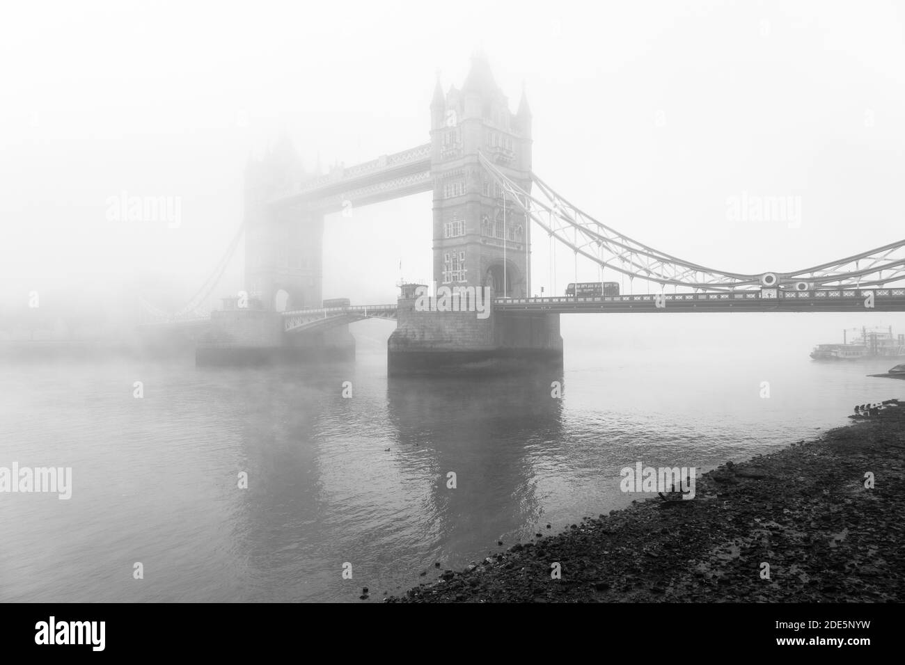 Black and White Tower Bridge e London Bus che guidano sul Tamigi in atmosfera nebbiosa e nebbia, condizioni atmosferiche umide sul Coronavirus Covid-19 Lockdown Day One, England, UK Foto Stock