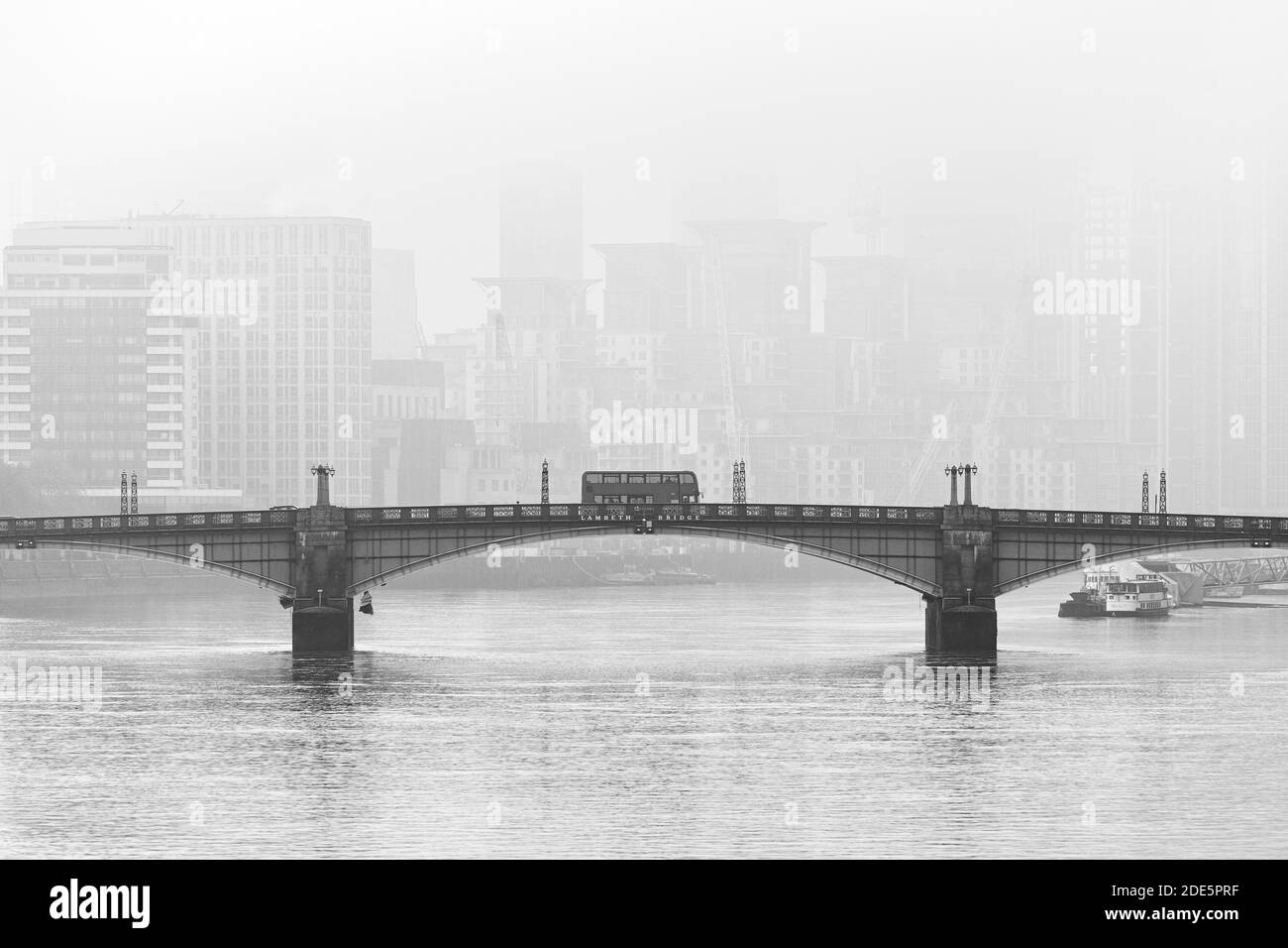 Skyline del centro di Londra in bianco e nero con l'iconico autobus di Londra che attraversa il Lambeth Bridge, con gli edifici nebbosi di grattacieli sparati in Coronavirus Covid-19 in Inghilterra, Regno Unito Foto Stock