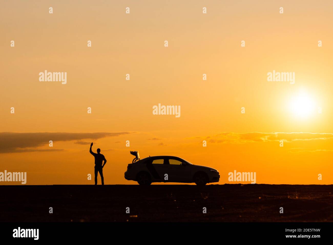 Il driver maschio ha alzato la mano e sta aspettando aiuto, l'auto non può muoversi ulteriormente dopo un guasto al tramonto, vista laterale, spazio di copia. Votazioni sul concetto di strada Foto Stock