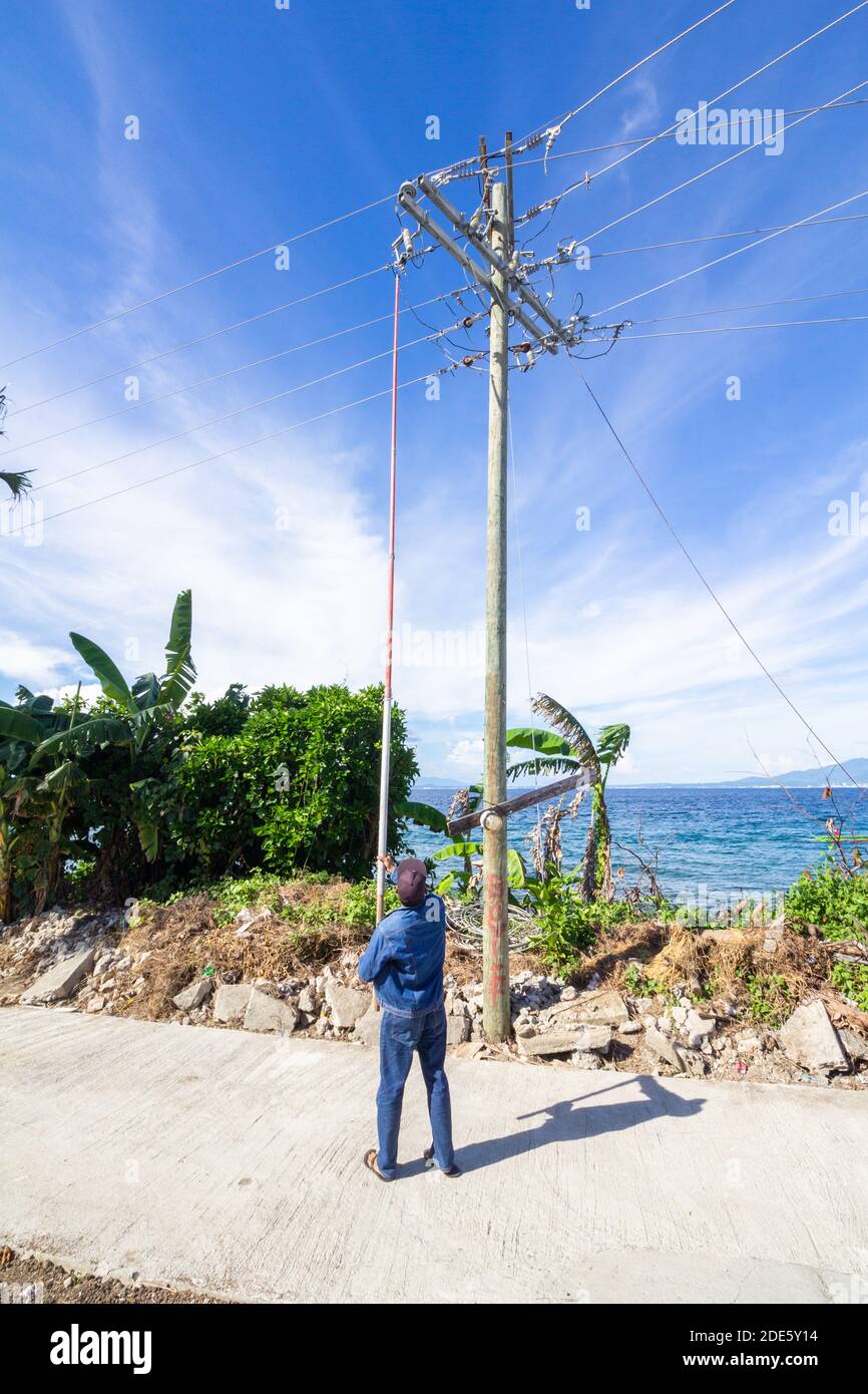 Un personale di servizio elettrico che lavora su un palo di servizio elettrico nell'isola di Tingloy, al largo di Batangas, Filippine Foto Stock