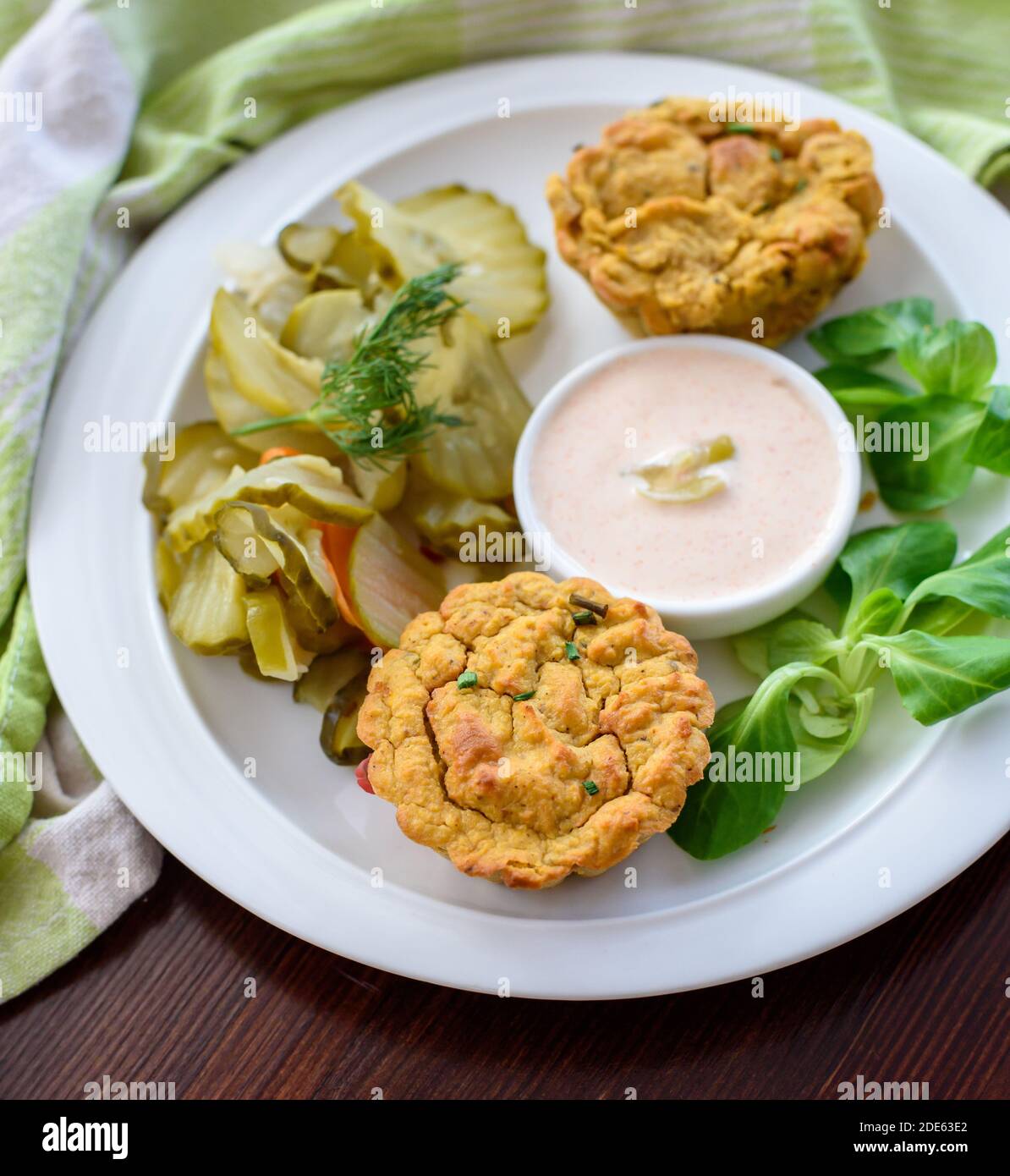 Primo piano su un antipasto a base di piante: Muffin vegetali vegani con salsa leggera di peperoncino-mayo e insalata di sottaceti di cetrioli, luce naturale Foto Stock