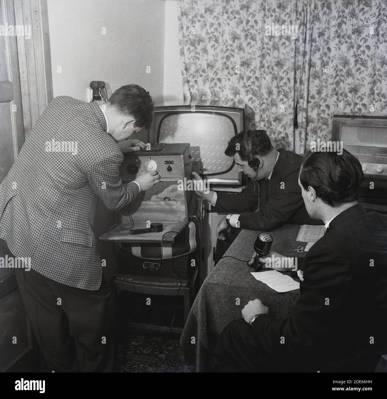 Anni '1960, storico, Pirate radio...inside una stanza in una casa, tre maschi coinvolti nella trasmissione radiofonica amatoriale....uno al microfono, uno con le cuffie e un altro che regola il trasmettitore, Londra, Inghilterra, Regno Unito. Foto Stock