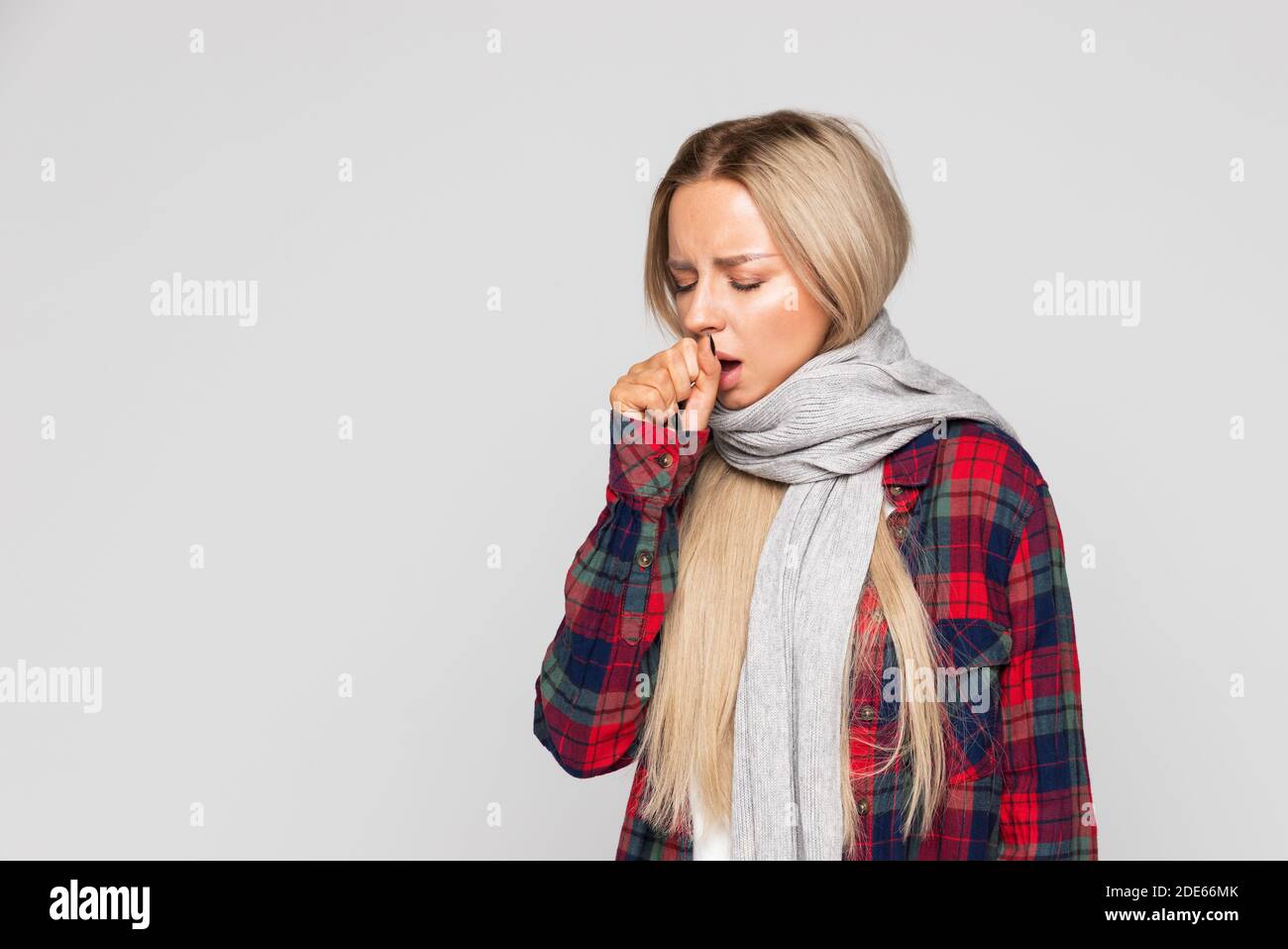 Donna in camicia controllata, sciarpa avvolta tosse, occhi chiusi. La donna malata ha influenza. Freddo, malattia. Foto Stock