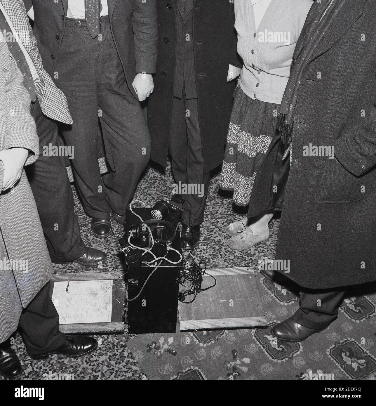 Anni '1960, storico, radio pirata..... All'interno di una stanza, un certo numero di adulti, con il volto nascosto, in piedi intorno a un dispositivo di trasmissione, Londra, Inghilterra, Regno Unito. La radio pirata si riferisce alla trasmissione non autorizzata, per lo più nota come la "radio offshore" che sorse in questo orecchio, ma descrive anche le emittenti terrestri senza licenza, le emittenti amatoriali che operano da case popolari. Foto Stock