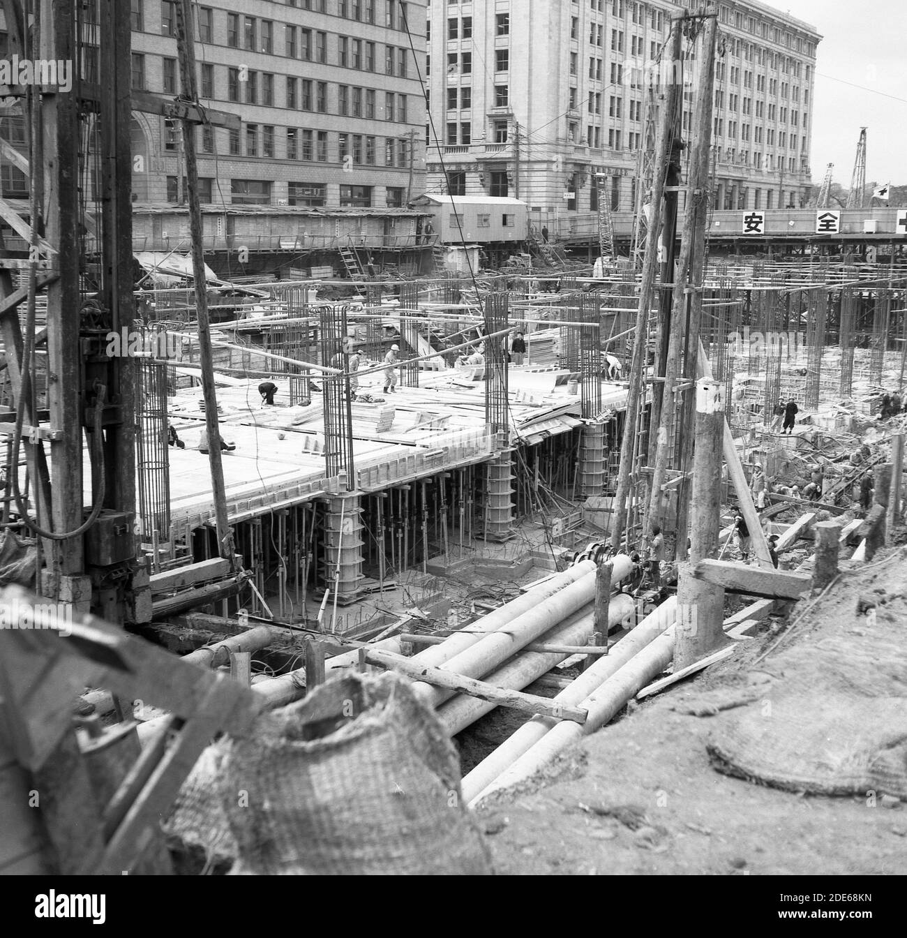 Anni '1960, storica, Tokyo, un grande cantiere in città per nuovi blocchi di torri, che mostra fondazioni sommerse e un piano è stato costruito. Foto Stock