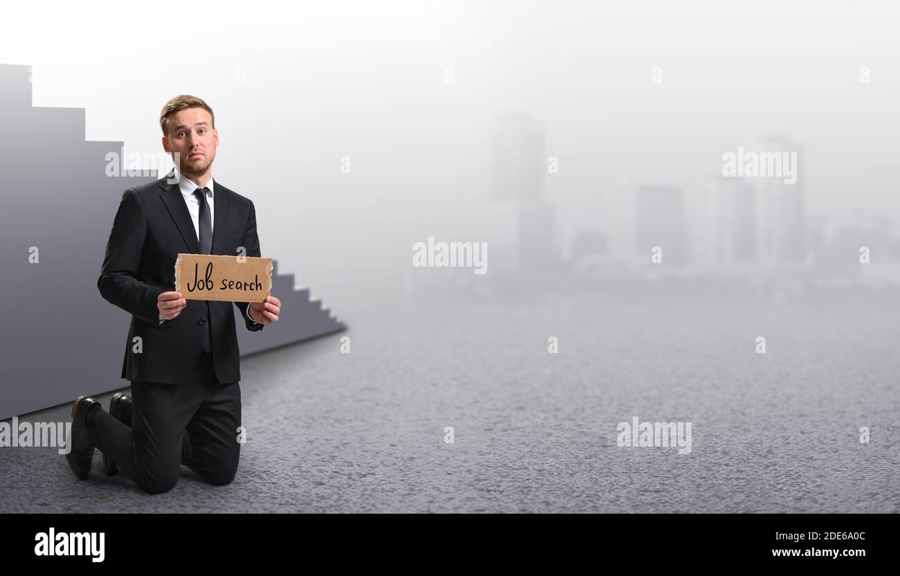 Licenziato manager triste che mostra poster di cartone con la ricerca di lavoro messaggio su sfondo grigio Foto Stock