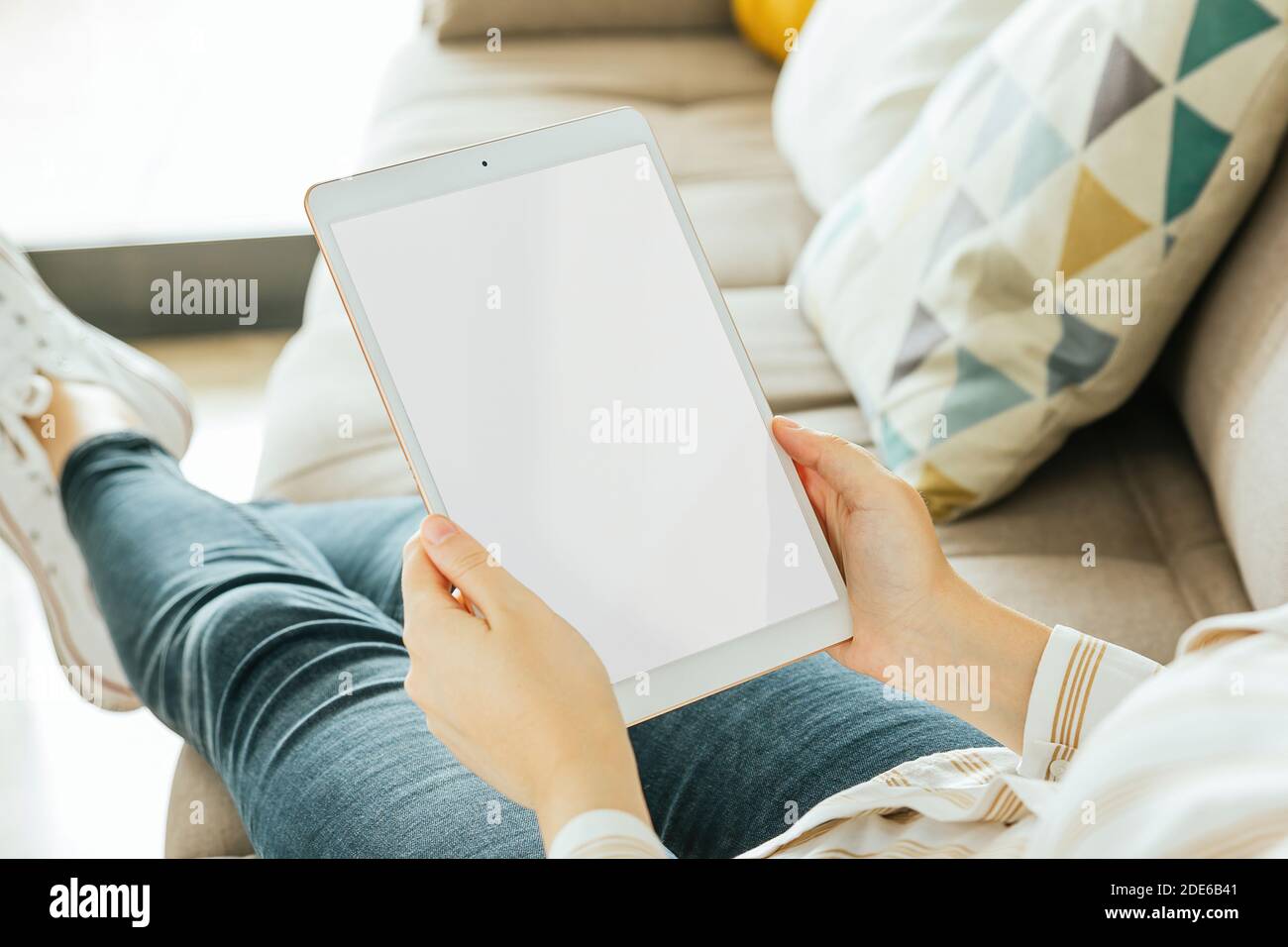 Tablet bianco schermo mockup tenuto da una donna che è seduto sul divano Foto Stock