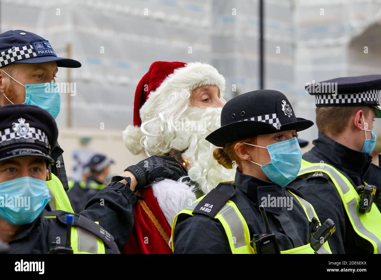 Londra, Regno Unito. - 28 Nov 2020: Un uomo vestito da Babbo Natale è portato via tra una pesante presenza di polizia a una protesta anti-blocco nella capitale. Foto Stock