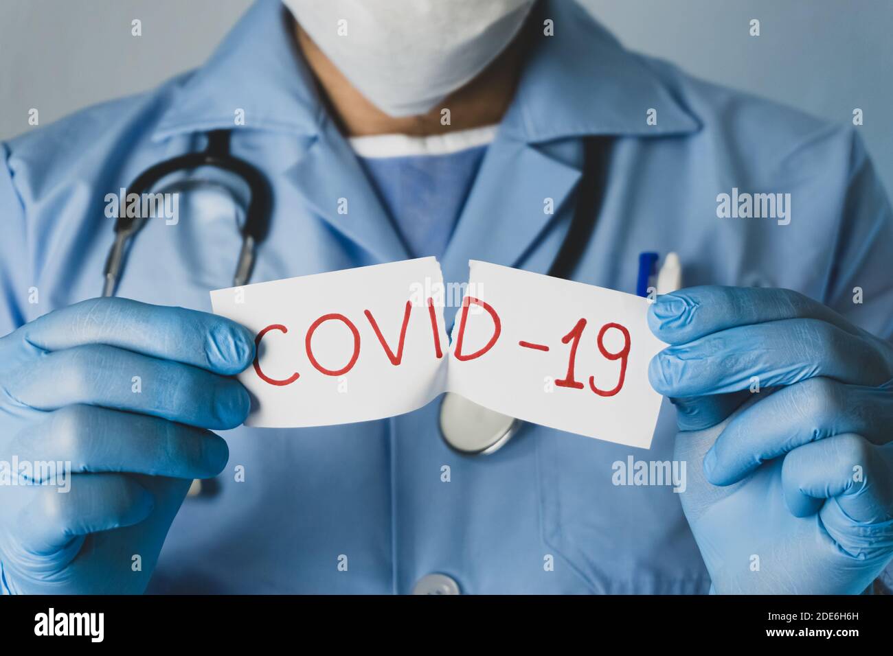Il medico strappa il white paper che dice Covid-19. Concetto di epidemia di coronavirus. Foto Stock