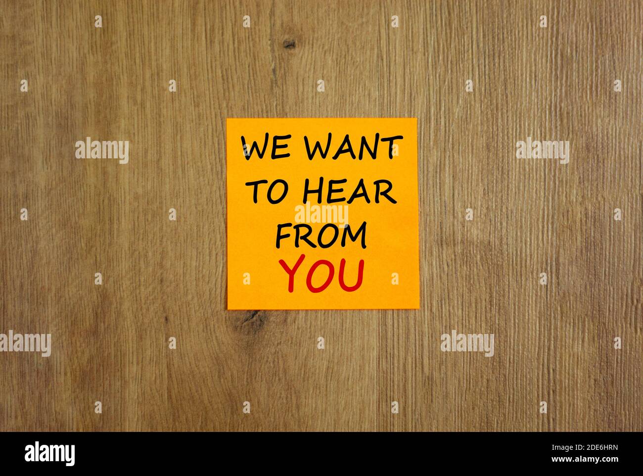 Foglio di carta arancione. Testo 'vogliamo sentire da voi'. Bellissimo sfondo in legno. Concetto di business e supporto, spazio di copia. Foto Stock