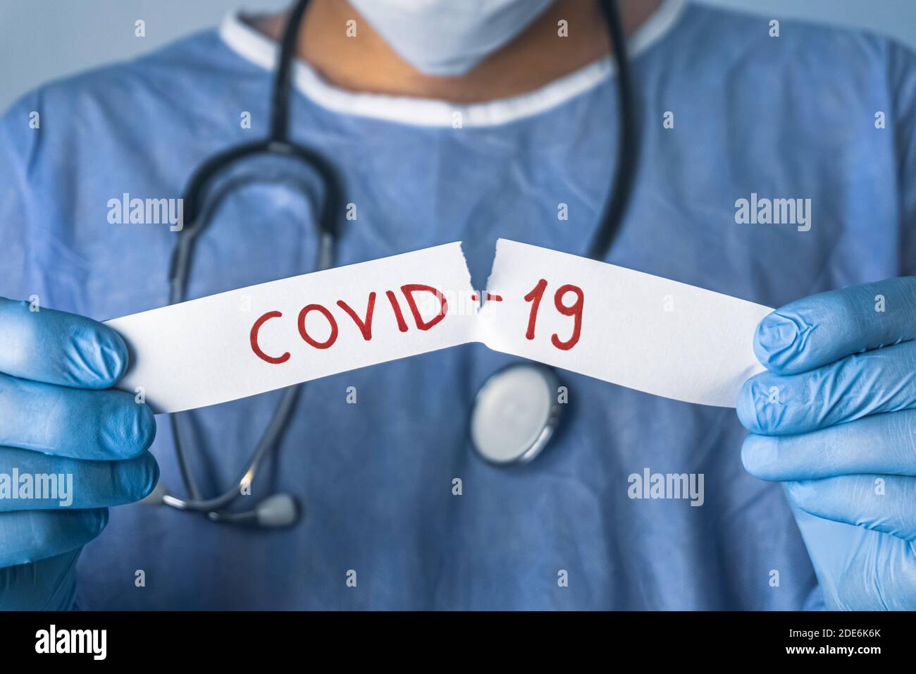 Il medico strappa il white paper che dice Covid-19. Concetto di epidemia di coronavirus. Foto Stock