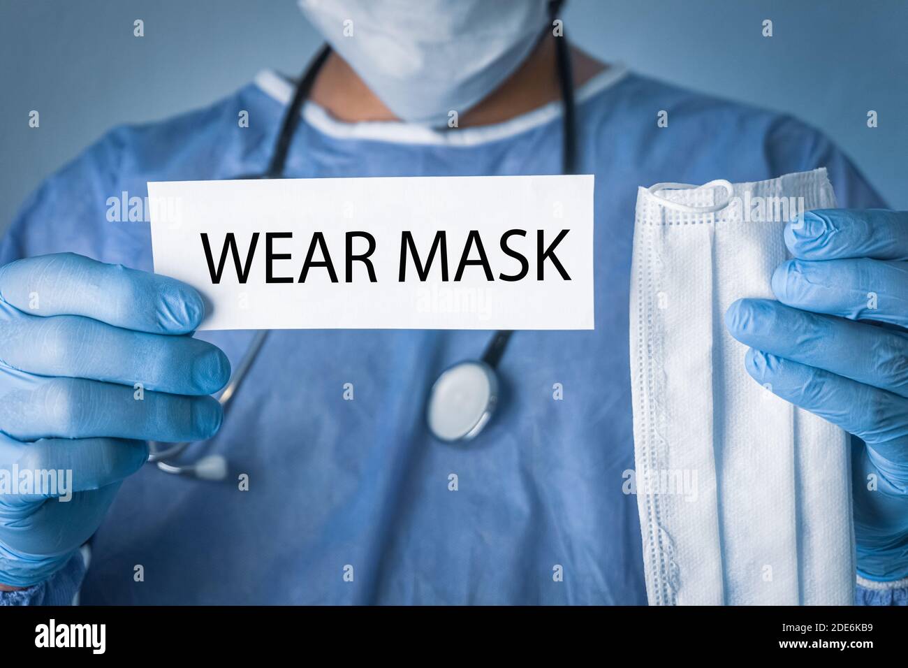 Foto concettuale per l'epidemia di COVID-19. Medico che tiene un foglio bianco che ha scritto maschera di usura. Foto Stock