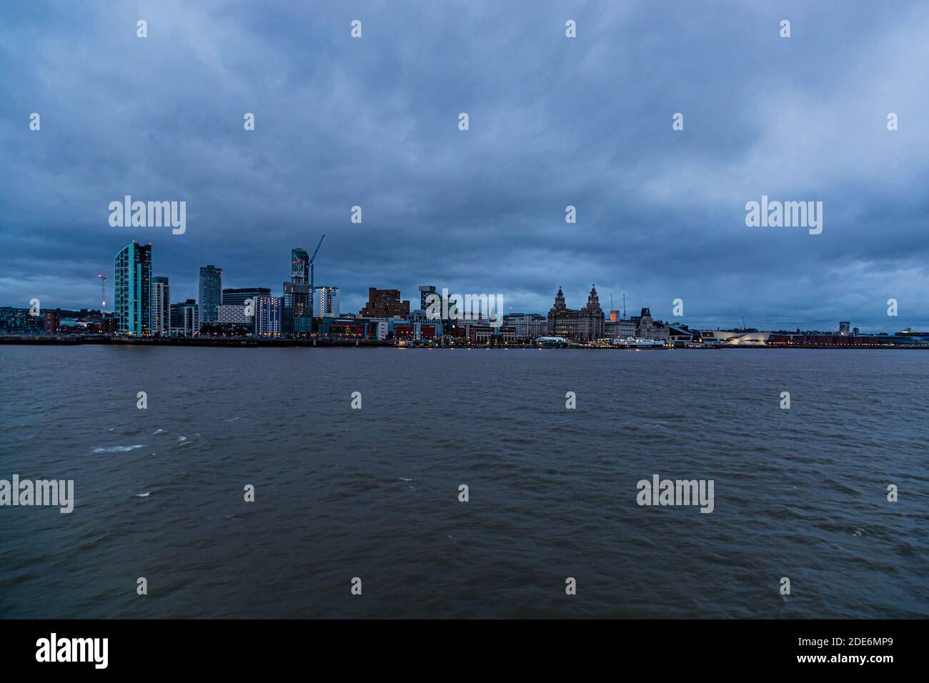 Lo skyline illuminato di Liverpool, Inghilterra, con le storiche "Three Graces" (Royal Liver Building, Cunard Building, Port of Liverpool Building), si estende lungo il fiume Mersey al crepuscolo, fotografato dal lato di Wirral vicino a Wallasey, vicino al tunnel Kingsway. Foto Stock