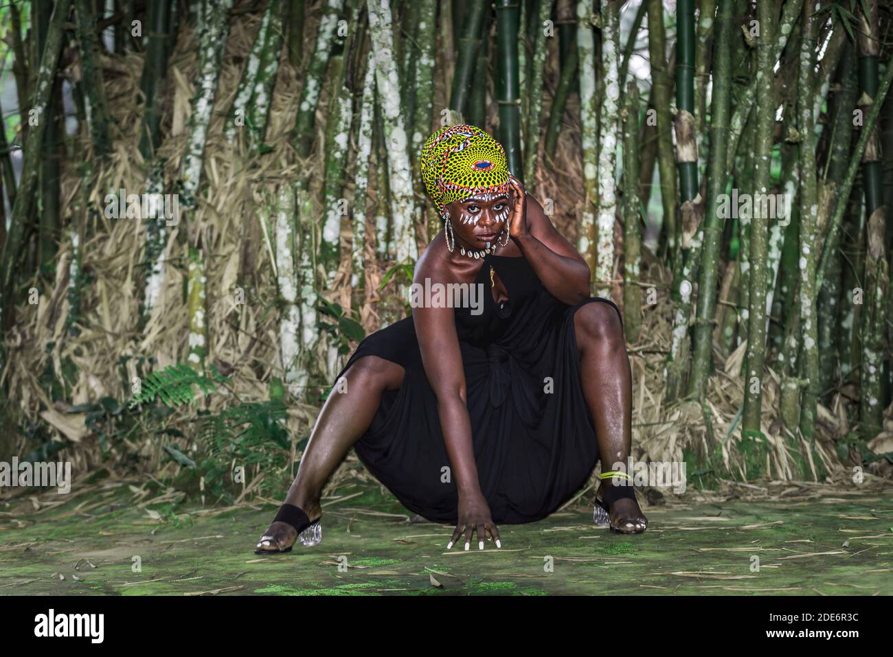 Donna africana seduta di fronte alla foresta di bambù con Africana Pittura di faccia in Aburi Ghana Africa occidentale Foto Stock