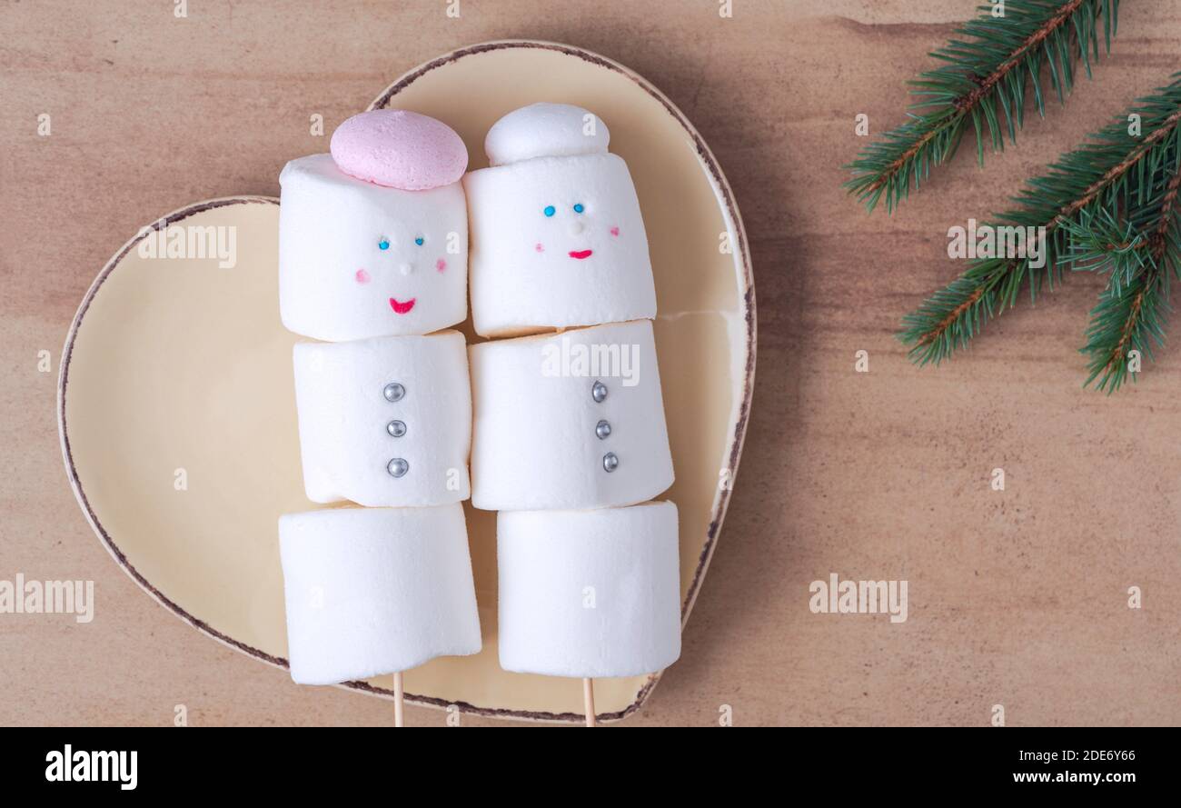 Simpatici pupazzi di neve marshmallow sulla piastra a forma di cuore Foto Stock
