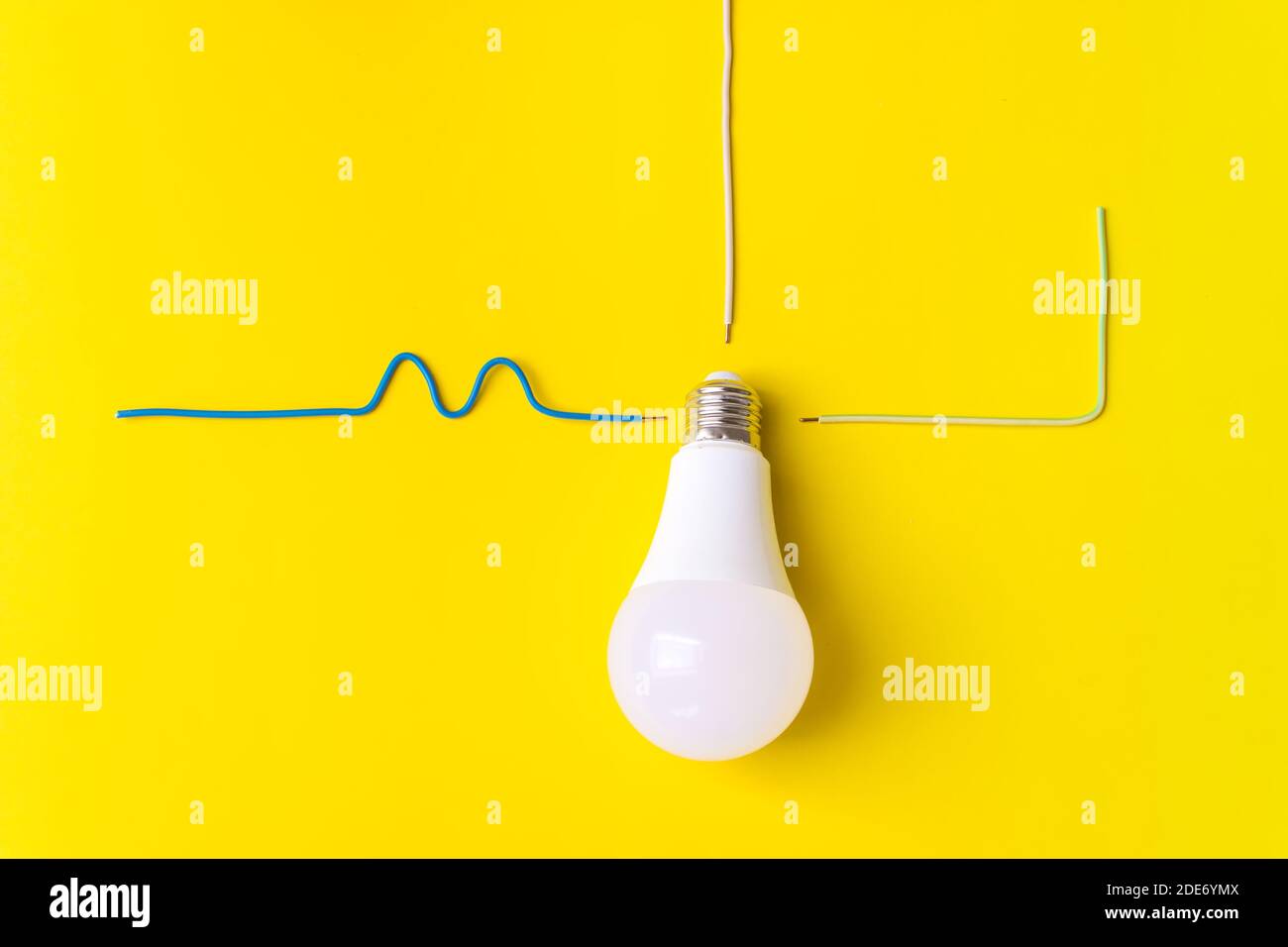 Lampadina a LED con filo collegato fase, zero, massa su sfondo giallo. Nuova tecnologia dell'energia, concetto di Eco Power. Spazio di copia. Risparmio energetico c Foto Stock