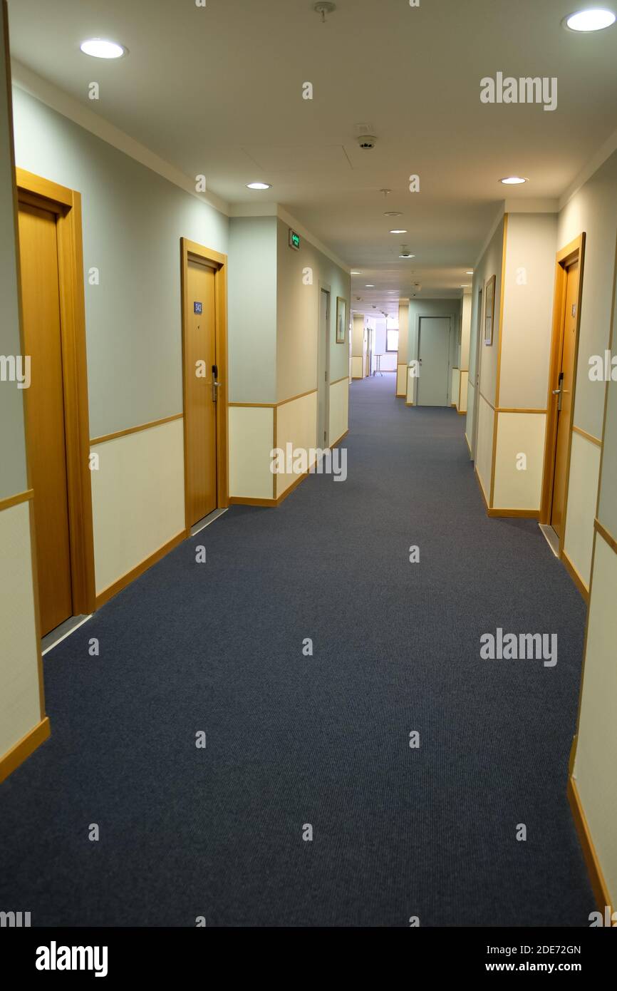 Una vista di un lungo corridoio nell'hotel, illuminato dalla luce del giorno. Concetto di vacanza, viaggio, quarantena, blocco, perdite di affari in hotel, hotel vuoti. Verticale Foto Stock