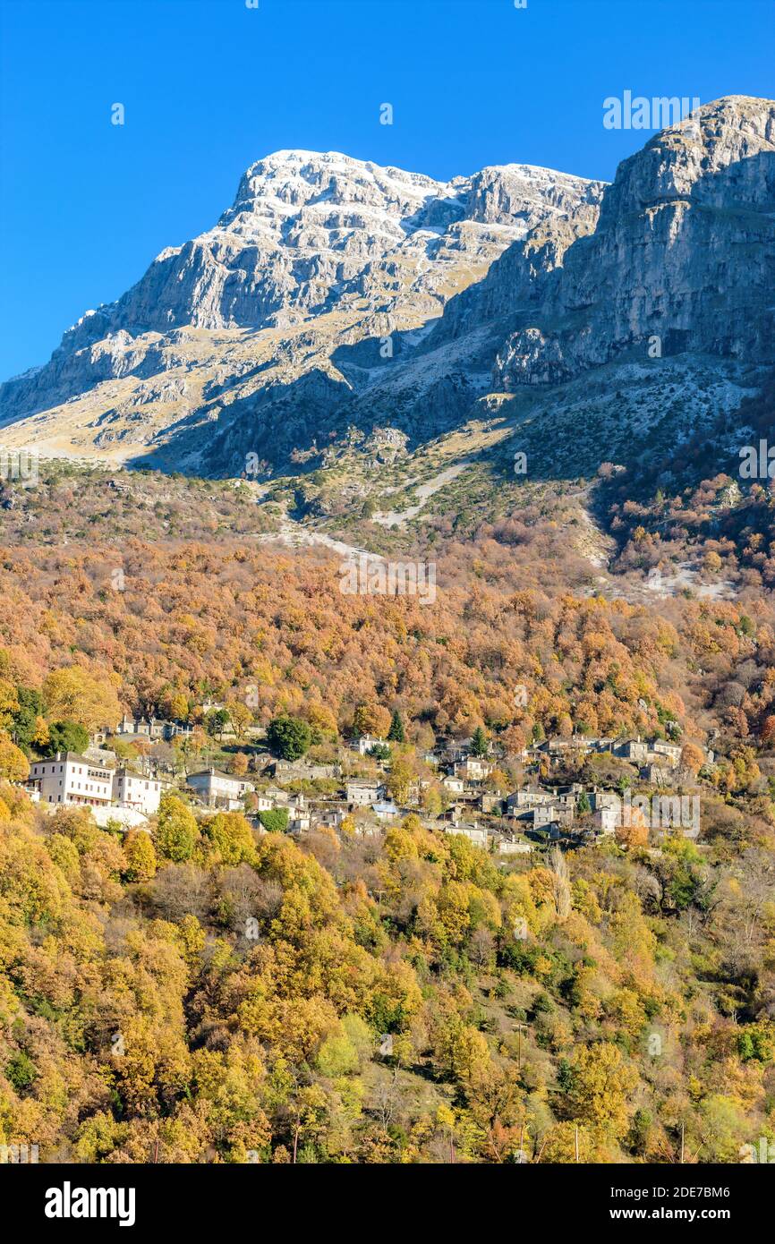 Vista del villaggio tradizionale Mikro Papigo con pietra edifici e astraka montagna come sfondo durante la stagione autunnale in zagori Grecia Foto Stock