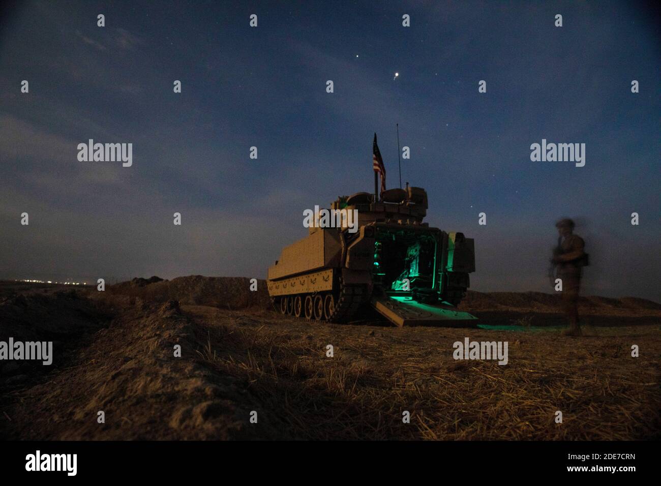 Un soldato statunitense si trova accanto ai veicoli da combattimento della fanteria M2 Bradley durante un checkpoint notturno del 30 ottobre 2020 nella Siria settentrionale. I soldati si trovano in Siria per sostenere l’operazione congiunta della task force per la risoluzione inerente ai combattenti dello Stato islamico. Foto Stock