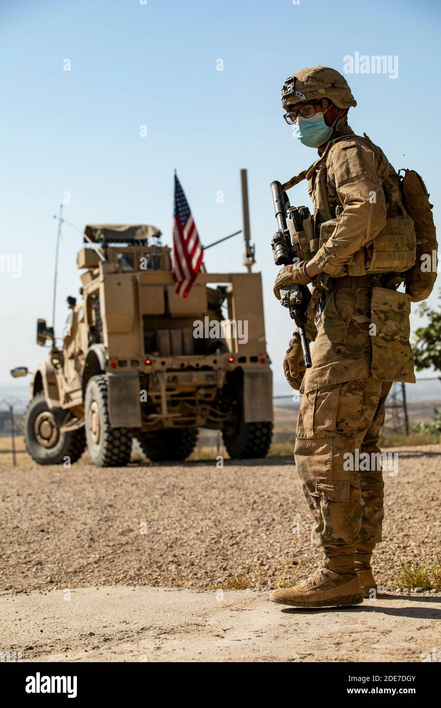 Un soldato dell'esercito degli Stati Uniti si trova a un punto di controllo con i veicoli di combattimento della fanteria di Bradley su una strada nella Siria settentrionale 26 ottobre 2020 vicino a Qamishli, Siria. I soldati si trovano in Siria per sostenere l’operazione congiunta della task force per la risoluzione inerente ai combattenti dello Stato islamico. Foto Stock