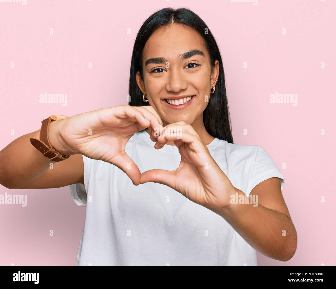 Giovane donna asiatica che indossa una t-shirt bianca casual sorridente nell'amore facendo il simbolo del cuore forma con le mani. Concetto romantico. Foto Stock