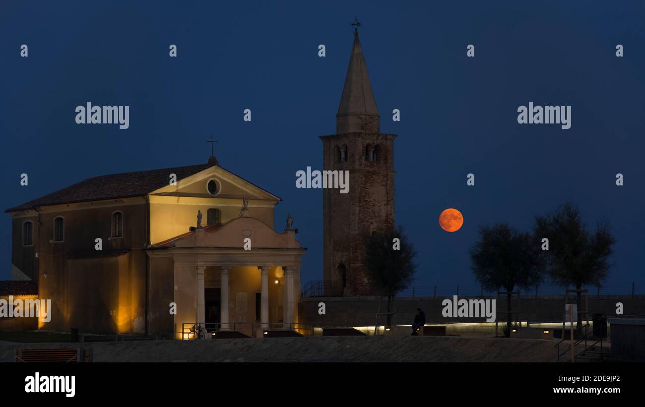 Santuario della Madonna dell`Angelo nel villaggio di Caorle in serata con una luna piena rossa Foto Stock
