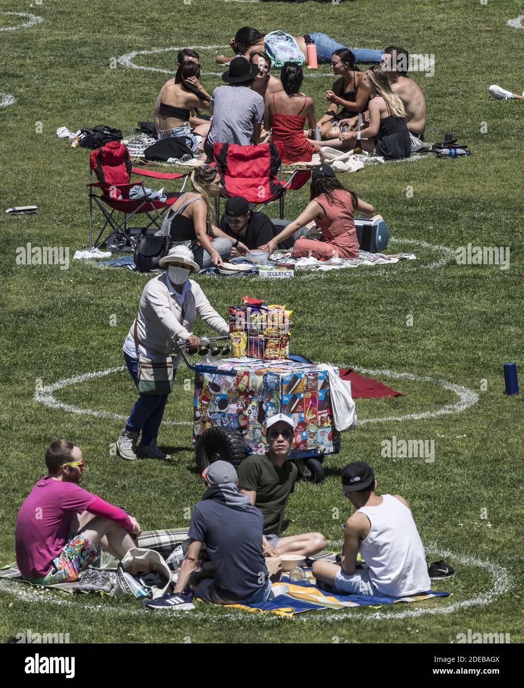 Un venditore di snack mascherato spinge il suo carrello attraverso i gruppi in circoli pre-disegnati nel Delores Park a San Francisco sabato 23 maggio 2020. Il clima caldo e un fine settimana di vacanza hanno portato fuori migliaia per praticare i loro propri marchi di distanziamento sociale. Foto di Terry Schmitt/UPI Foto Stock