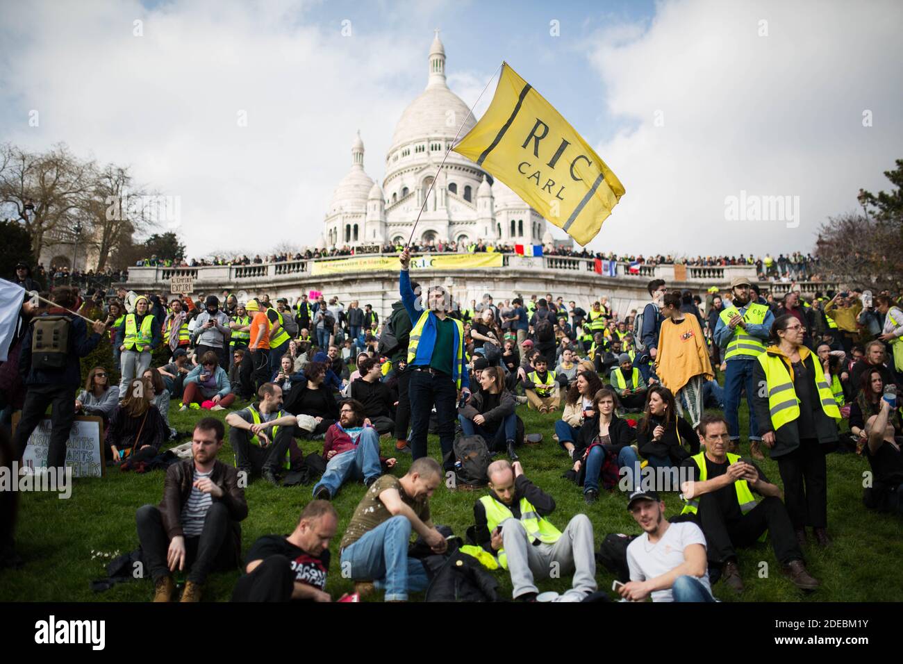 I manifestanti di Yellow Vest si riuniscono di fronte alla Basilica del Sacro cuore a Montmartre, il manifestante ha una bandiera gialla per la R.I.C., Referundum d'Initiative citoyenne, a Parigi il 23 marzo 2019, durante una manifestazione anti-governativa chiamata dal movimento 'Gialle Vest' (Gialle jaunes). I manifestanti hanno nuovamente colpito le strade francesi il 23 marzo, per una diciannovesima settimana consecutiva di protesta a livello nazionale ( atto 19 ) contro le politiche del presidente francese e il suo stile di governo top-down, i costi elevati della vita, le riforme fiscali del governo e per una giustizia più 'sociale ed economica.' Foto di Raphael Lafargue/ABACAPRES Foto Stock