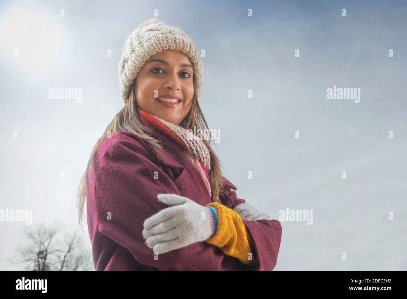 Donna vestita con un soprabito sorridente indossando un cappuccio con la mano si è piegata Foto Stock