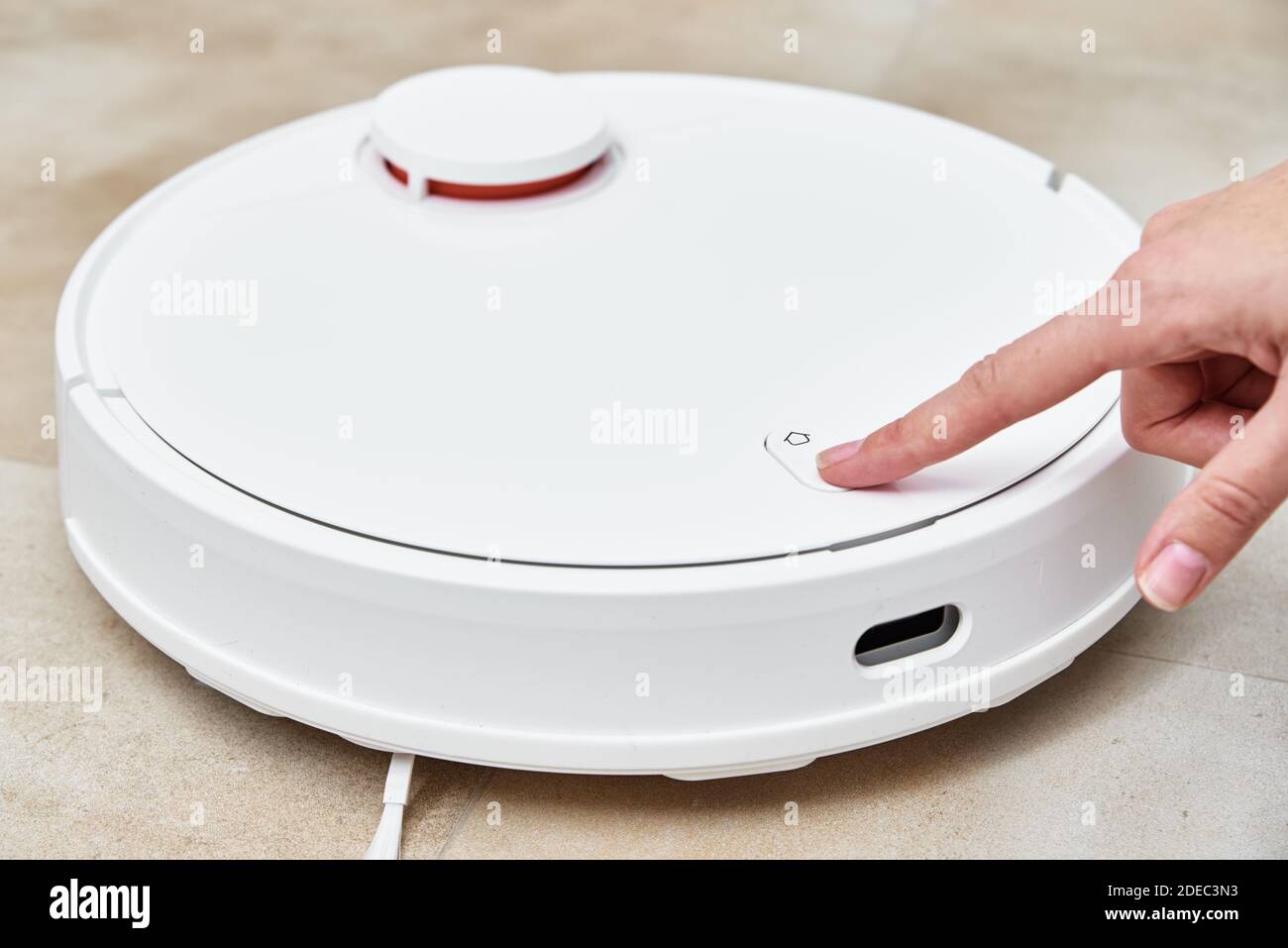 Premere manualmente il pulsante di avvio sull'aspirapolvere robot. Casa moderna e intelligente Foto Stock