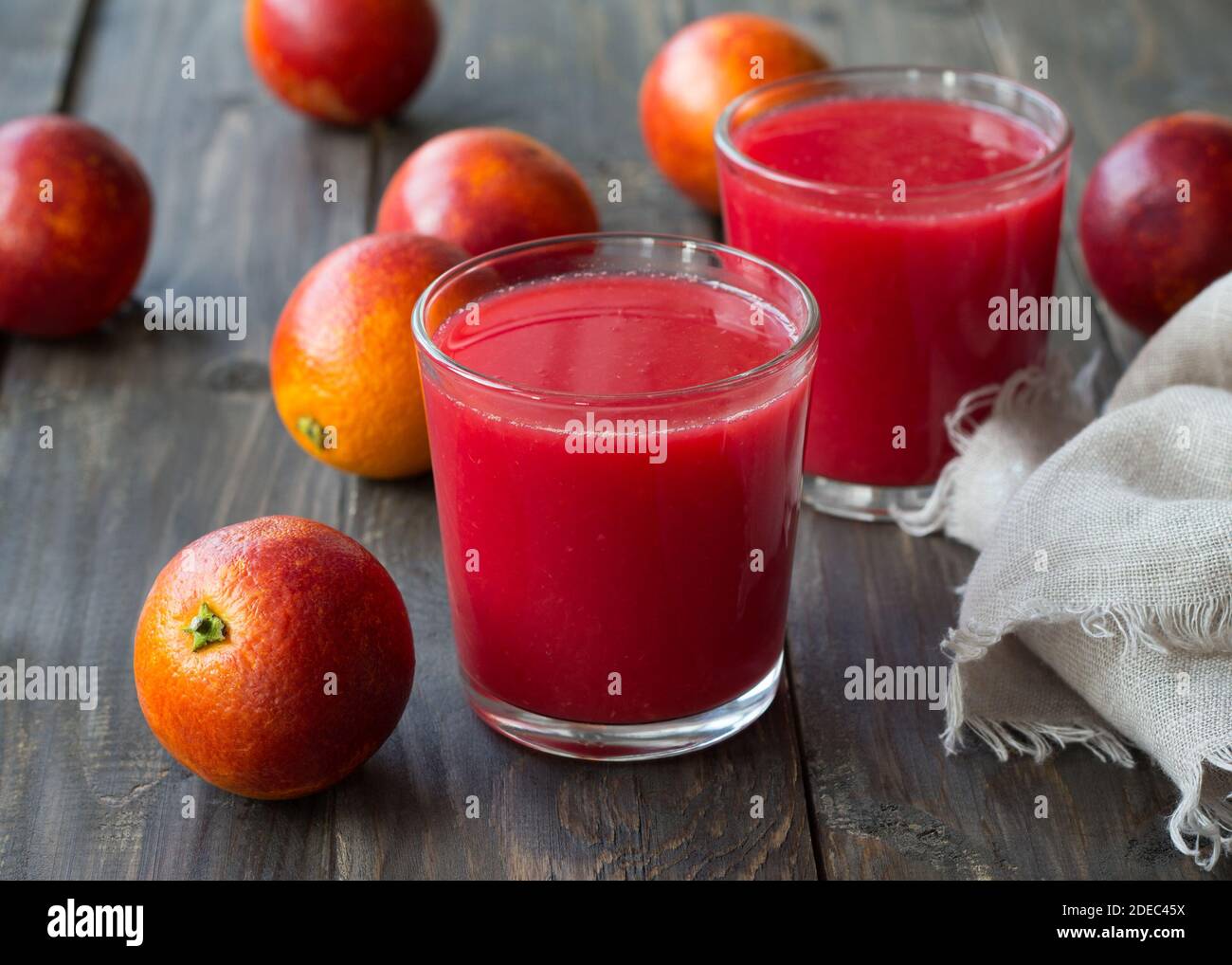 Spremuta fresca di arance di sangue in bicchieri con arance fresche intere su un tavolo di legno, fuoco selettivo Foto Stock