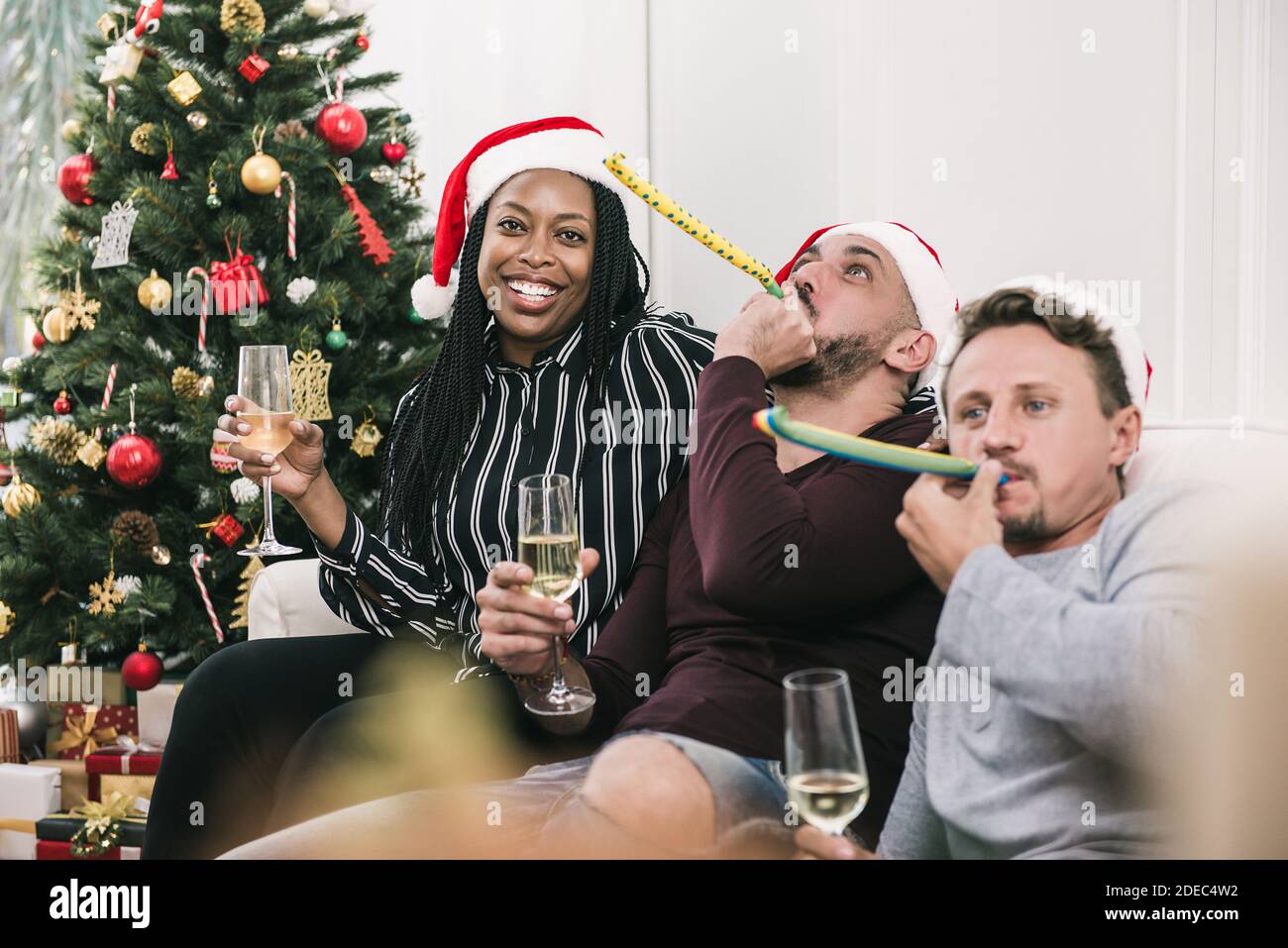 Donna afroamericana con gruppo di amici che festeggiano il Natale a. champagne da bere in casa Foto Stock