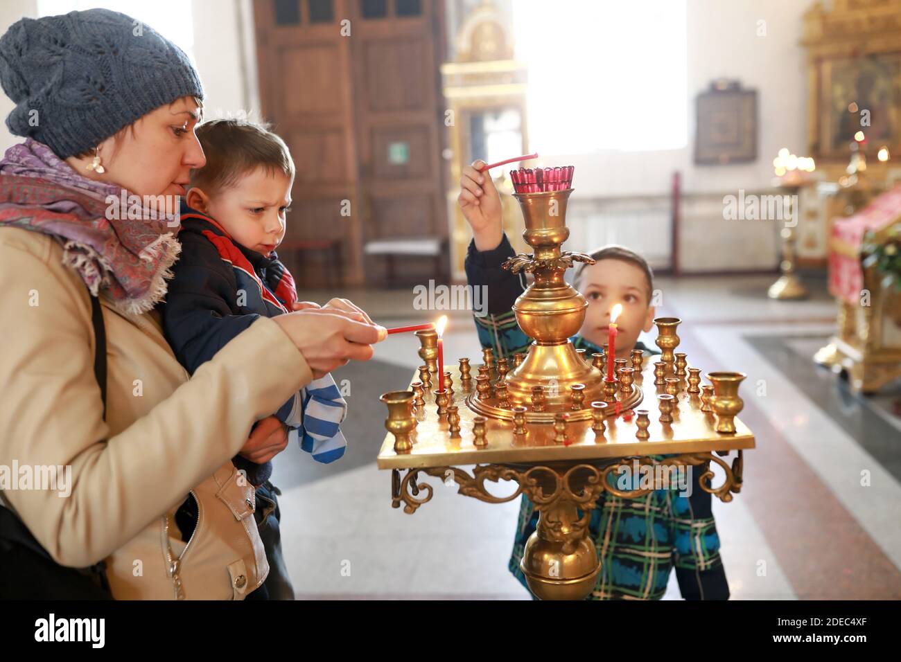 Mamma e figli illuminano le candele nella chiesa ortodossa russa Foto Stock
