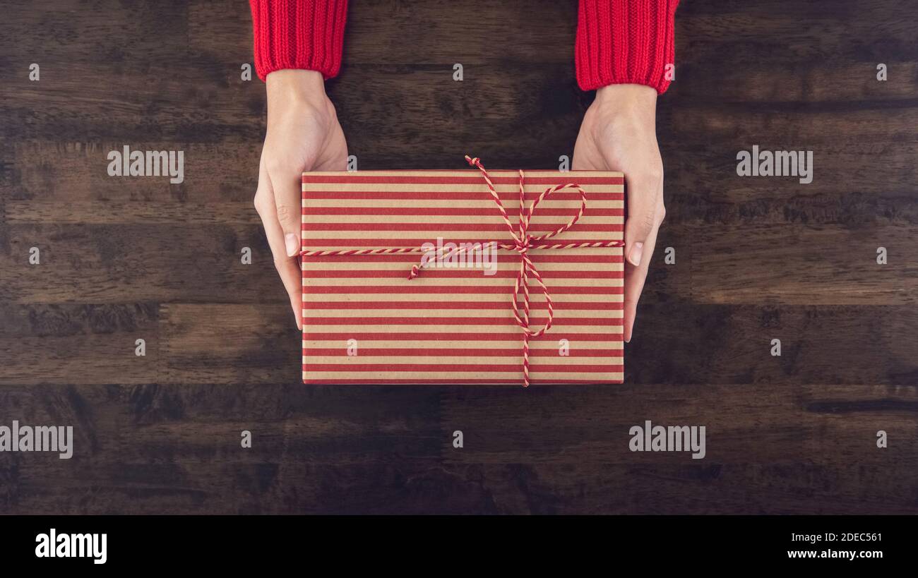 Mani donna che danno scatola regalo christmas vista dall'alto su legno sfondo della tabella Foto Stock