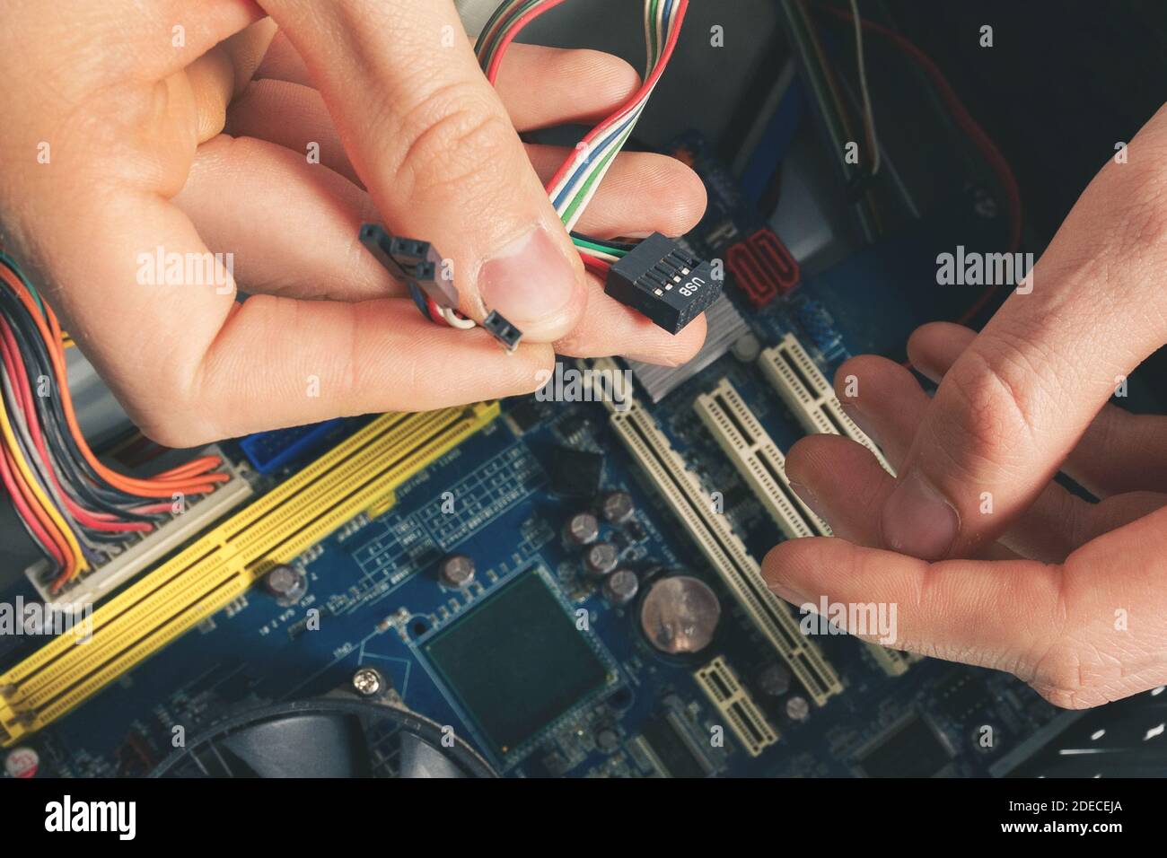 Il riparatore collega i cavi nel computer. Riparazione e smontaggio di apparecchiature informatiche. Foto Stock