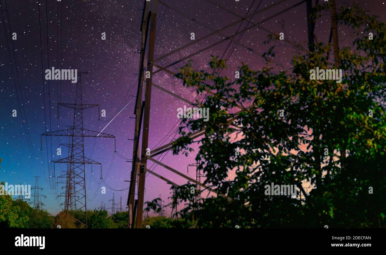 Polo ad alta tensione con Via Lattea sul cielo. Vista industriale delle linee ad alta tensione. Foto Stock