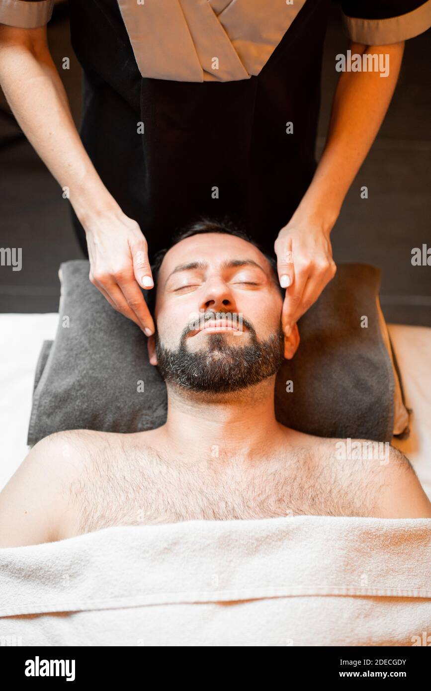 L'uomo bearded riceve un massaggio facciale, distendendo al salone di bellezza, vista dall'alto Foto Stock