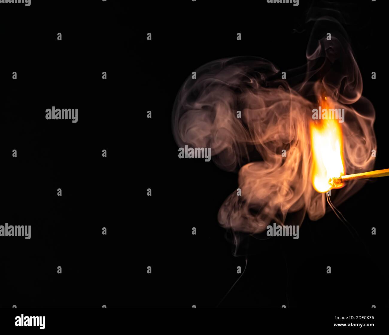 Singolo match che cattura sul fuoco con soffio di fumo che lo circonda, isolato su sfondo nero . Foto di alta qualità Foto Stock
