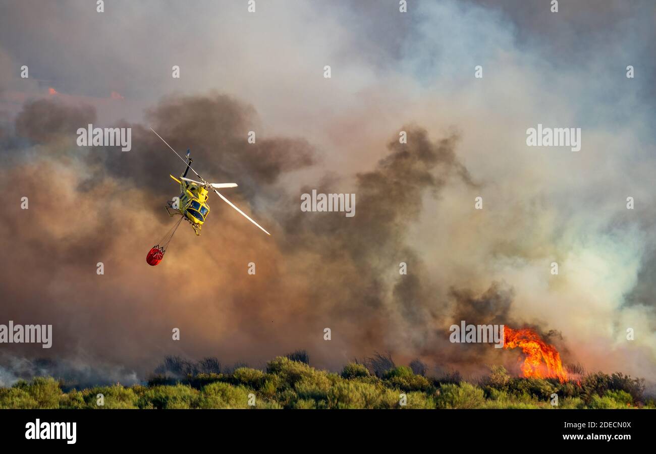 Fumo e fuoco enorme sfondo e elicottero con bambi secchio Foto Stock