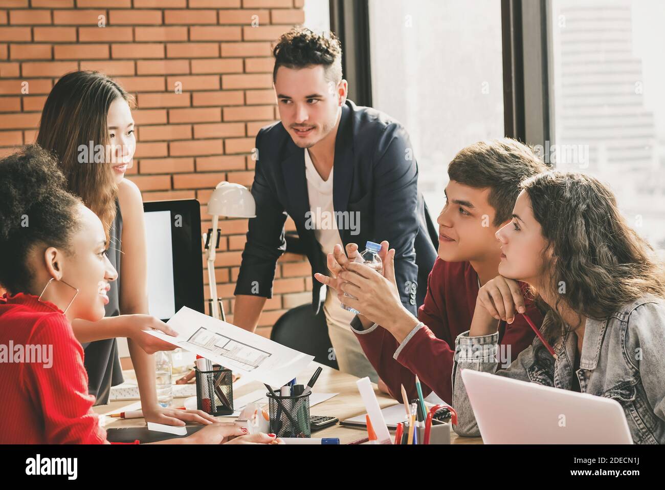 Designer di interni Millenial maschile e femminile in abbigliamento casual business condivisione di idee e progetti durante la riunione di brainstorming nell'area di lavoro dell'ufficio Foto Stock