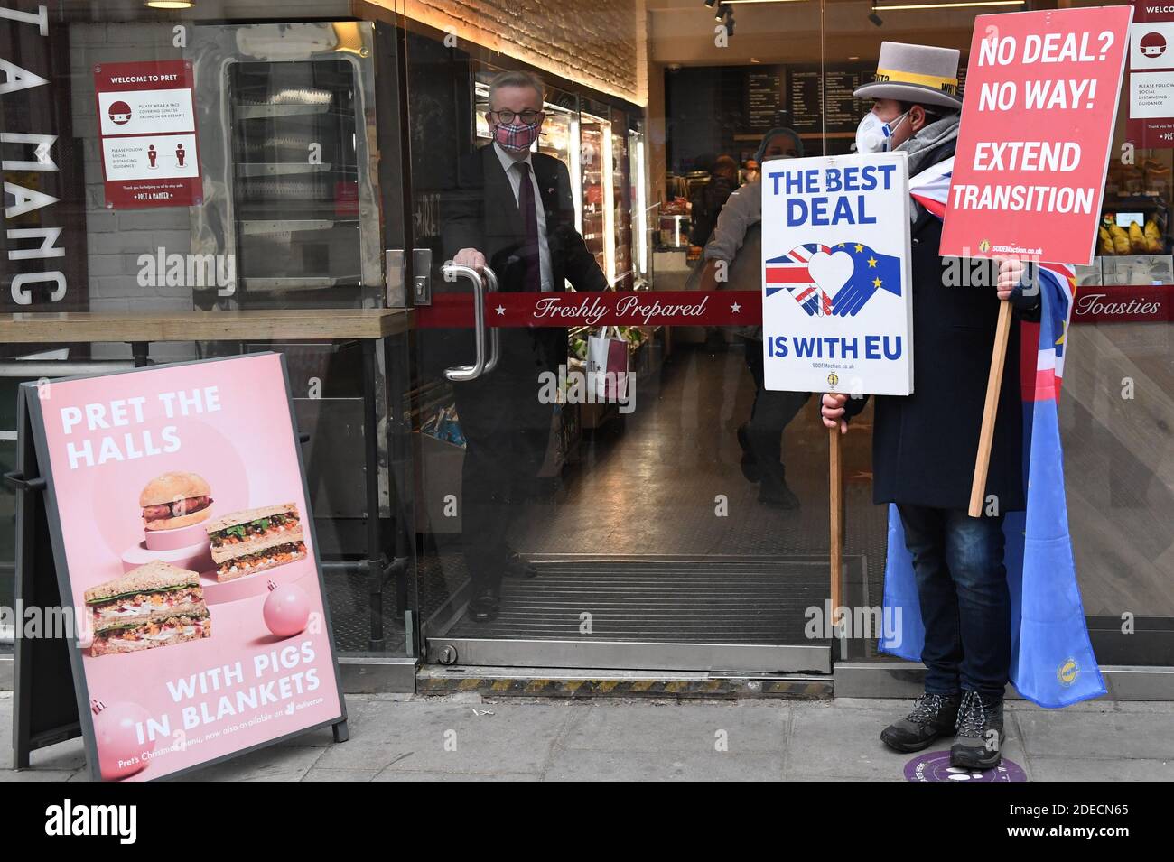 Il Cancelliere del Ducato di Lancaster, Michael Gove, raccoglie il suo caffè mattutino da una caffetteria nel centro di Londra, mentre un manifestante anti-Brexit lo aspetta all’esterno (destra) mentre le trattative per concludere un accordo commerciale post-Brexit continuano. Foto Stock